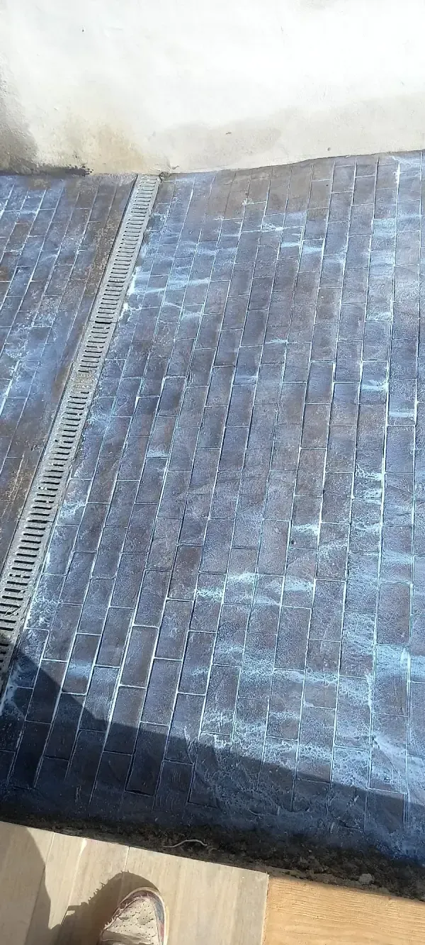 Primer plano de un camino adoquinado con un canalón de drenaje que corre a lo largo del costado.