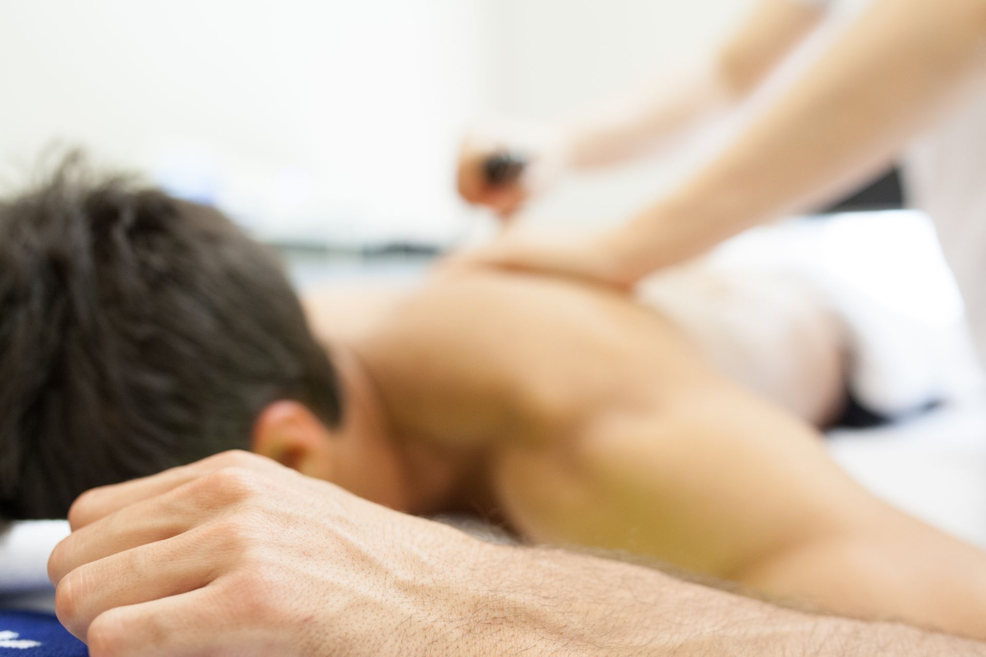 Person, die eine Rückenmassage erhält, Hände des Therapeuten üben Druck aus.