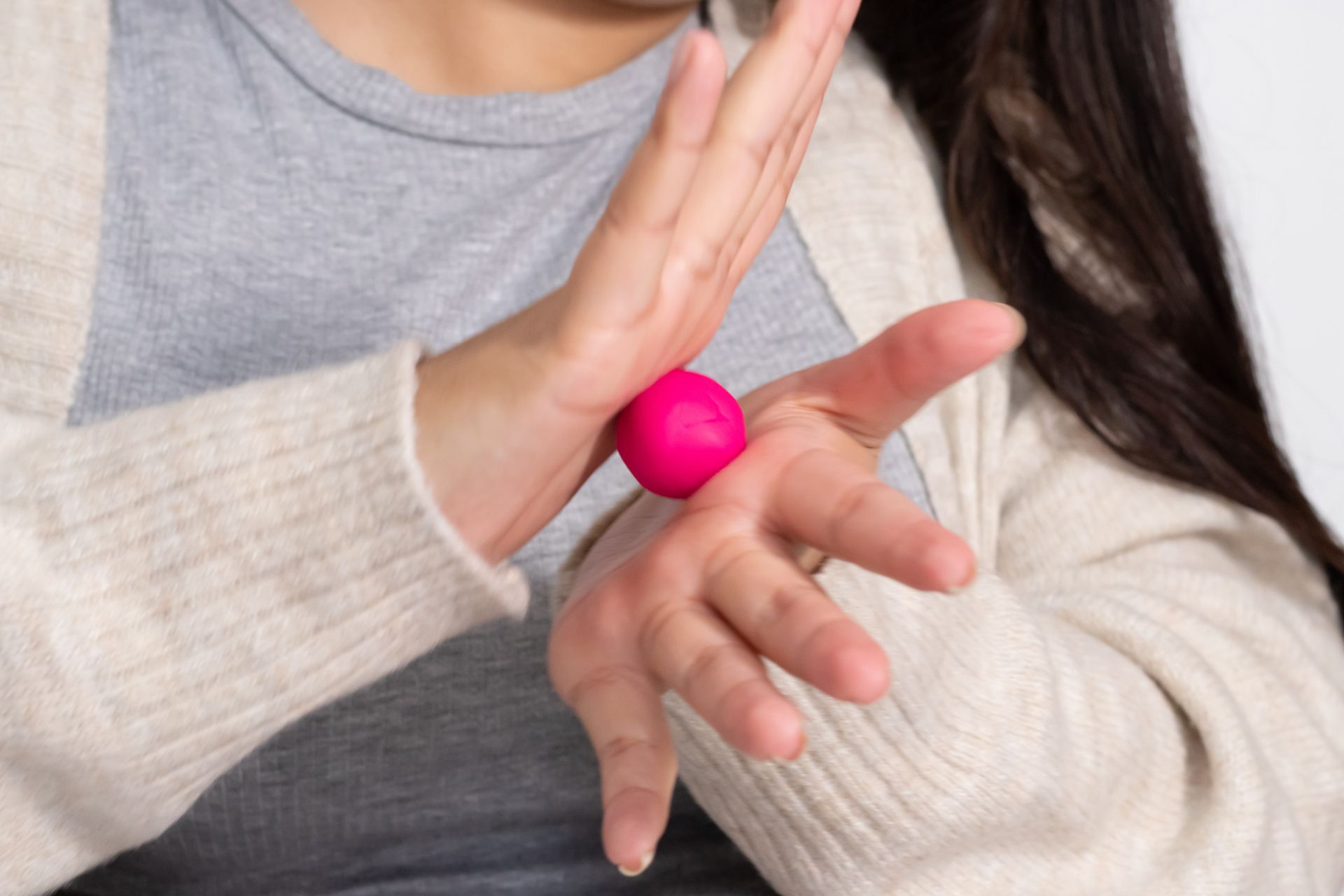 Eine Person formt mit den Händen eine rosa Tonkugel.