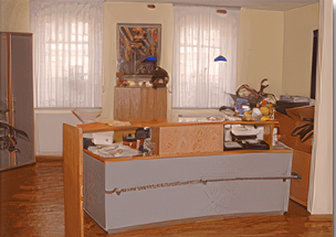 Wartezimmer mit drei Stühlen, einem Schrank mit Fernseher und einer Tür, die in einen anderen Raum führt.