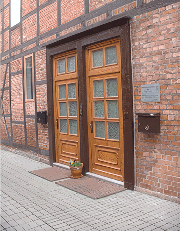 Medizinischer Untersuchungsraum mit Untersuchungstisch, Stühlen und Fenster mit Aussicht.