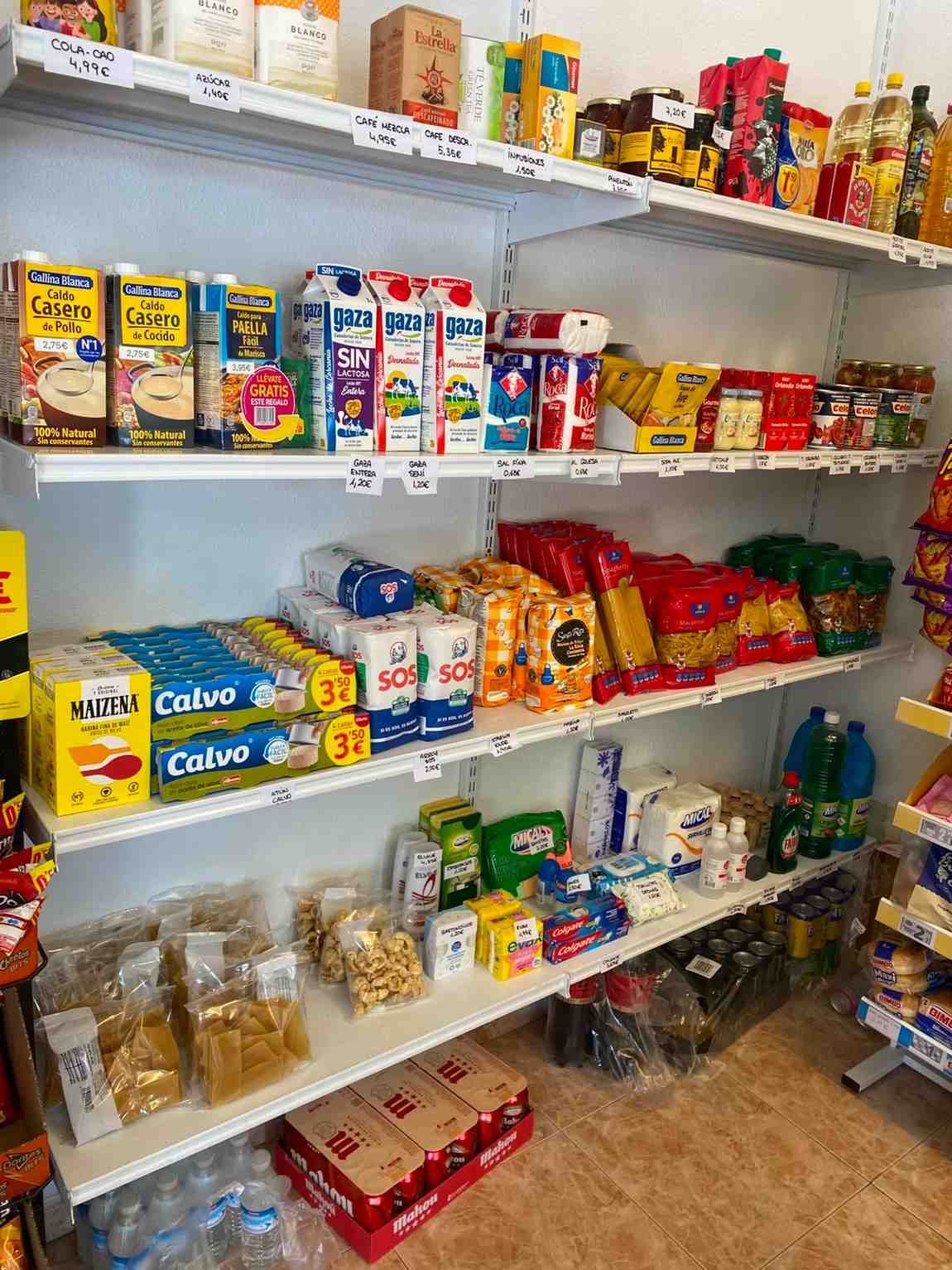 Estantes de la despensa repletos de conservas variadas, cereales, pasta y aperitivos.