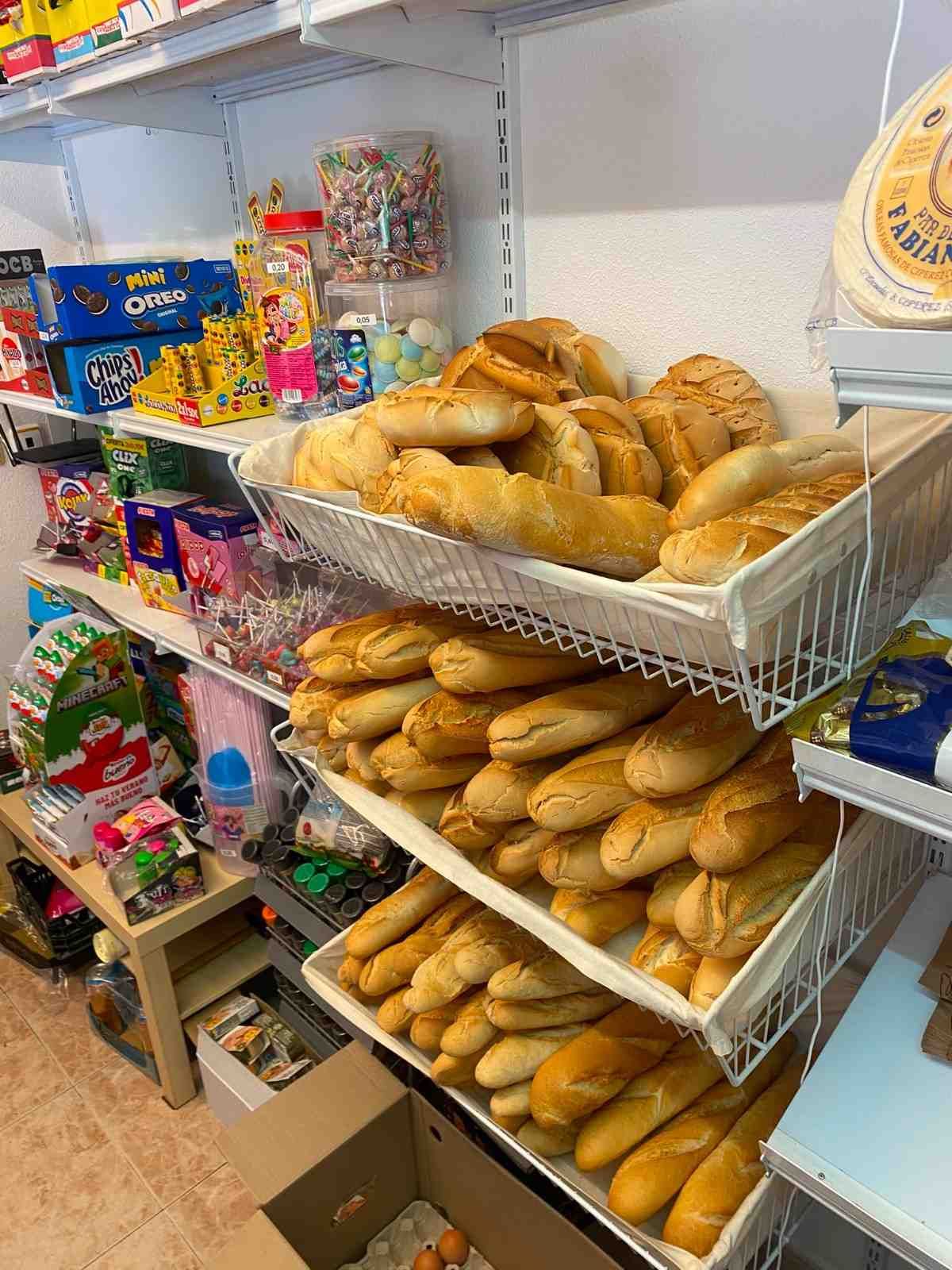 Estanterías con panes y pasteles variados en un pequeño pasillo de una tienda.