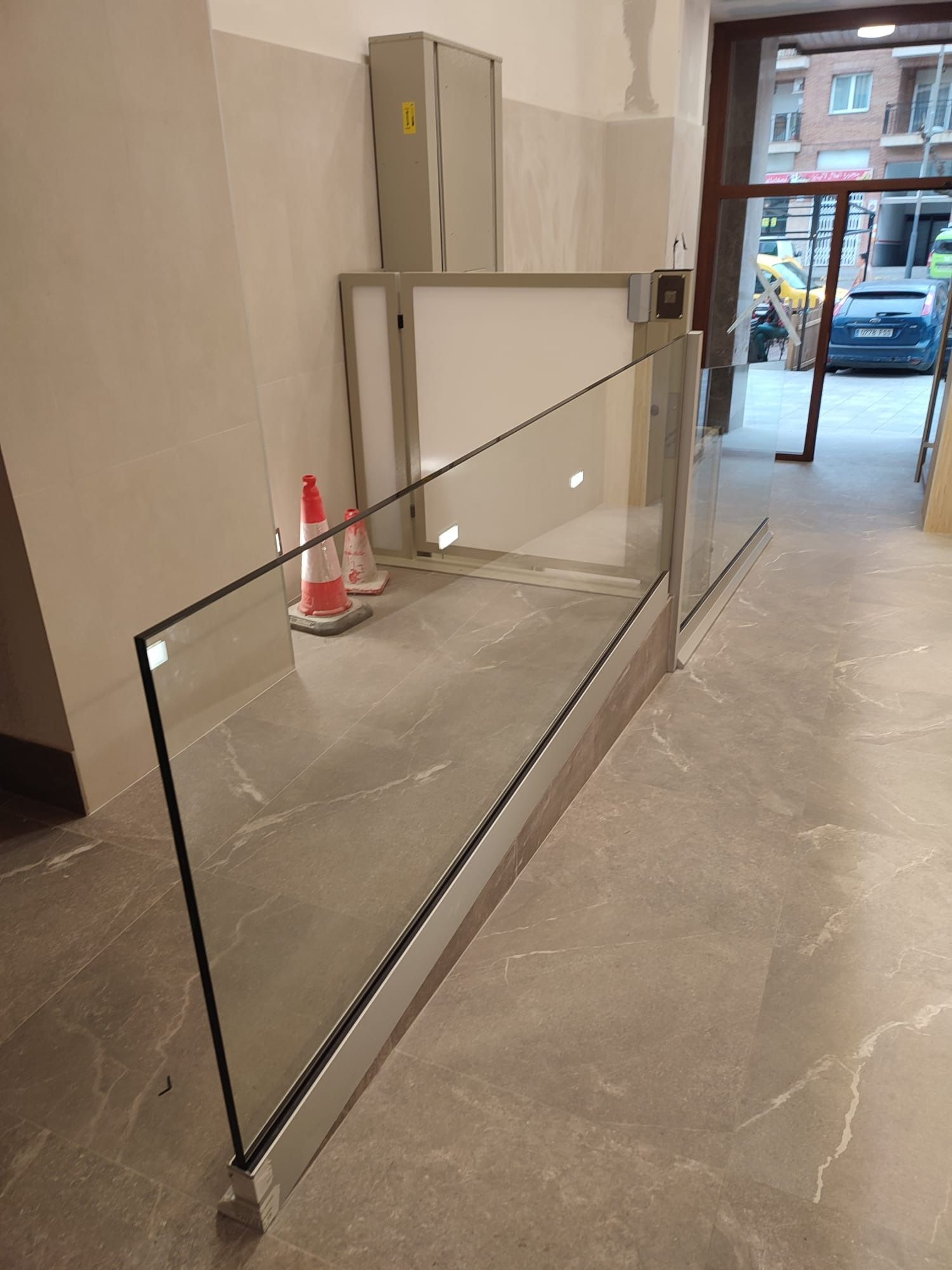 Gran panel de vidrio apoyado en el vestíbulo, cerca de una escalera y de las puertas de entrada