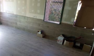 Habitación vacía con suelo de madera gris, paneles decorativos en las paredes y algunas cajas junto a la pared