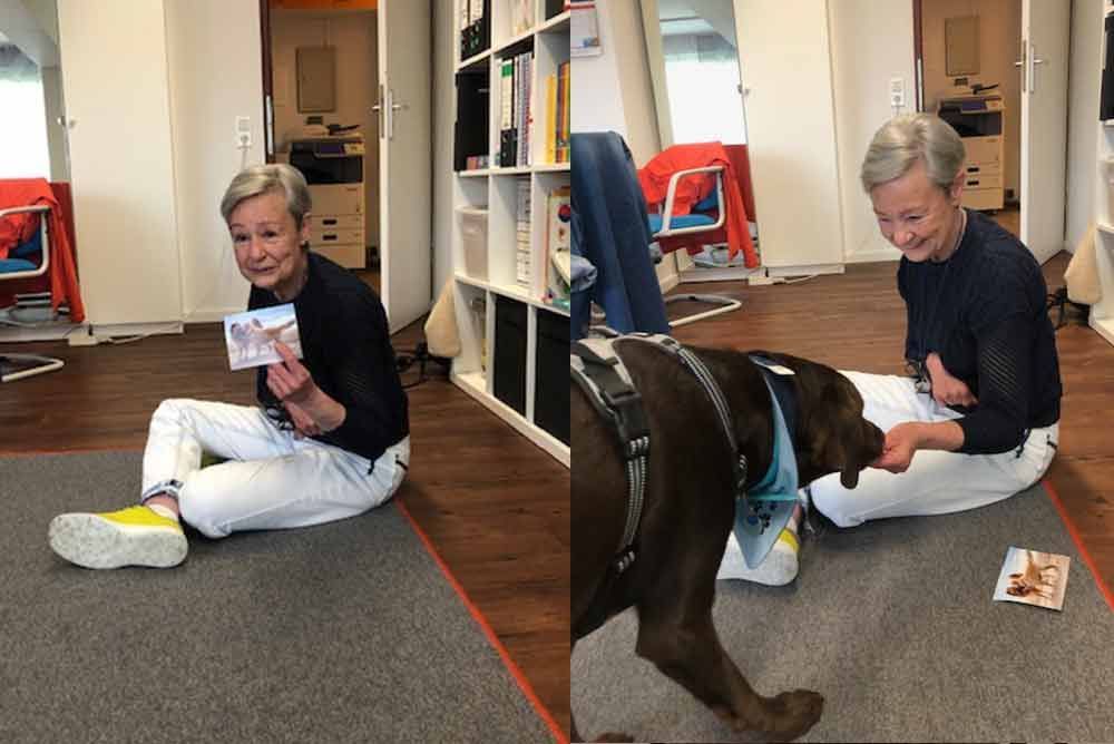 Eine Frau sitzt auf dem Boden und spielt mit einem Hund.