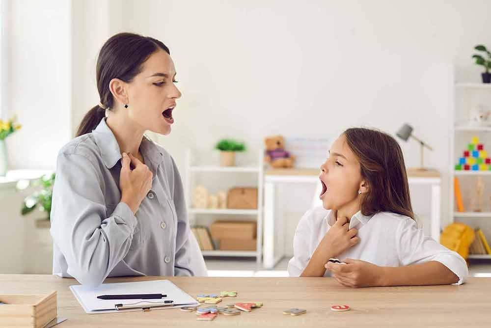 Eine Frau spricht mit einem kleinen Mädchen, während sie an einem Tisch sitzt.