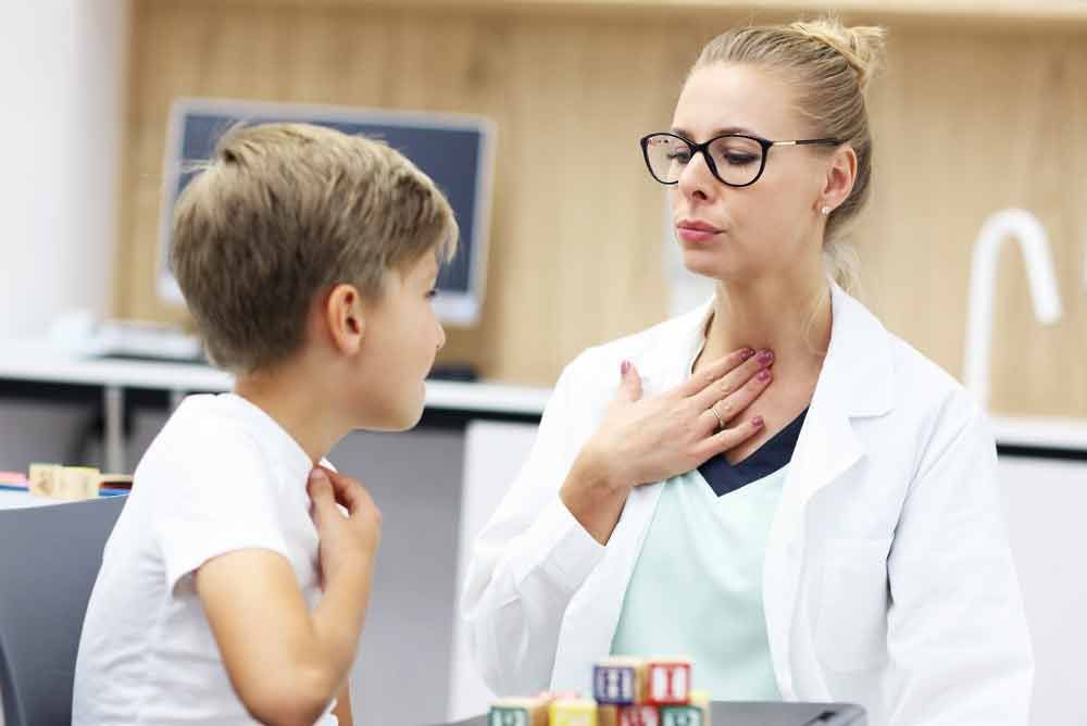 Eine Frau spricht in einem Klassenzimmer mit einem kleinen Jungen.