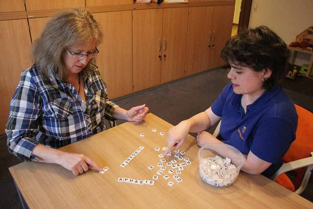 Zwei Frauen sitzen an einem Tisch und spielen Scrabble.