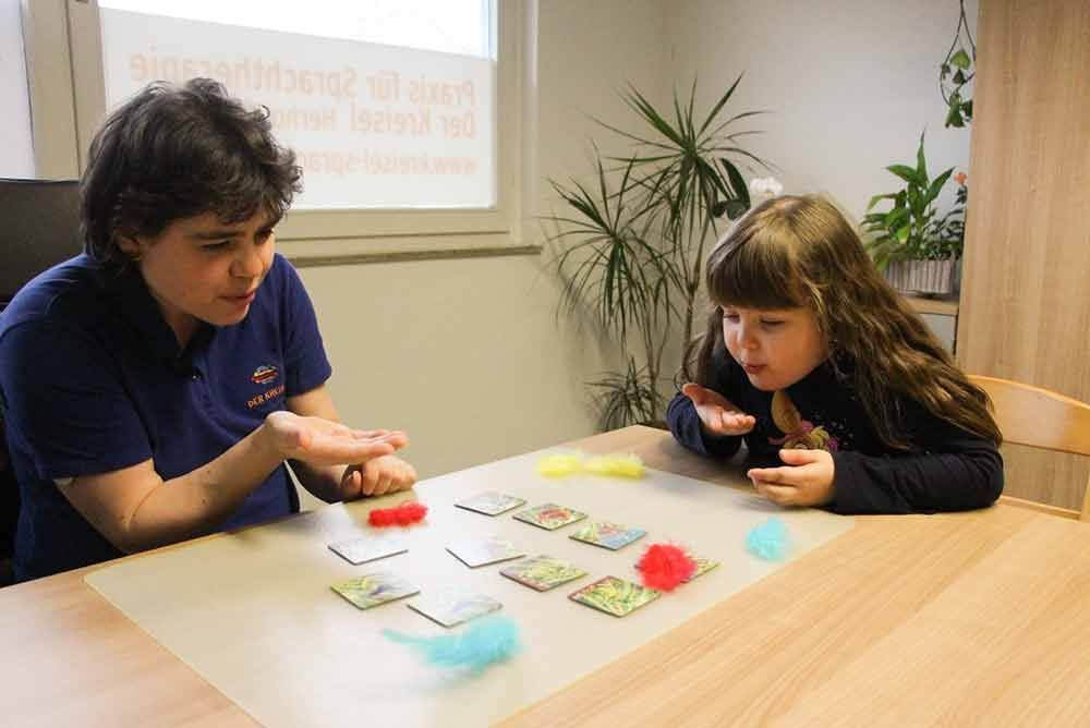 Eine Frau und ein kleines Mädchen sitzen an einem Tisch und spielen ein Spiel.