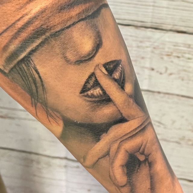 Ein Tattoo einer Frau, die ihren Mund mit ihrem Finger bedeckt