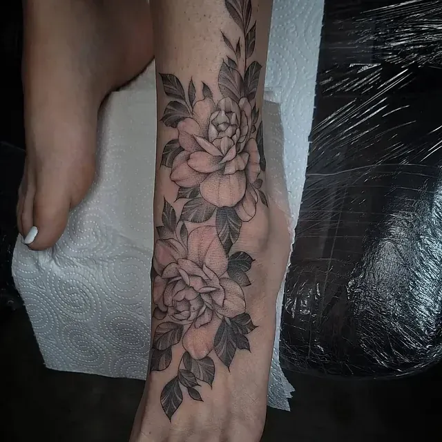 Eine Frau hat eine Blumentätowierung auf ihrem Fuß.