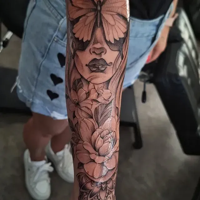 Eine Frau hat ein Tattoo mit einem Schmetterling und Blumen auf ihrem Arm