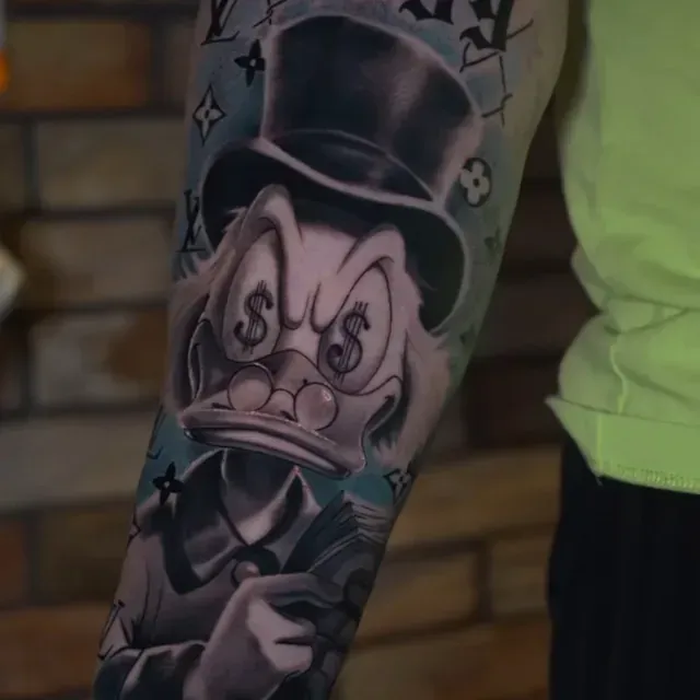 Eine Person hat ein Tattoo von Mr. Duck auf dem Arm