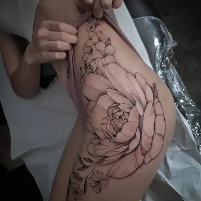 Eine Frau hat eine Rose auf ihrem Oberschenkel tätowiert