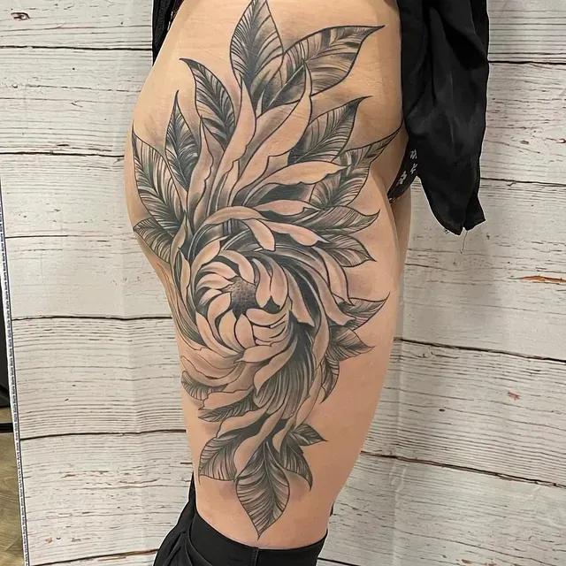 Eine Frau hat eine Blumentätowierung auf ihrem Bein.