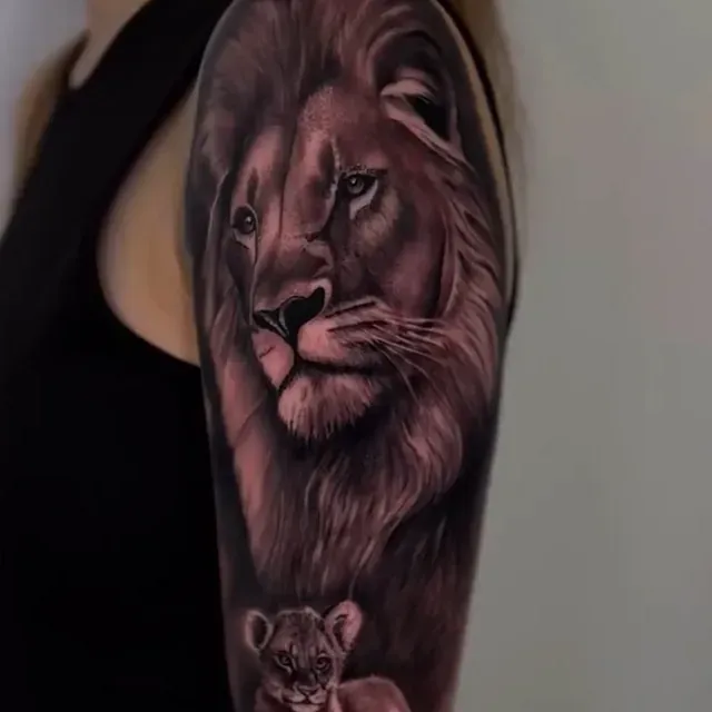 Eine Frau hat eine Tätowierung von einem Löwen und einem Löwenjungen auf ihrem Arm.