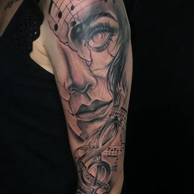 Eine Frau hat eine Tätowierung mit einem Frauengesicht und Musiknoten auf ihrem Arm.
