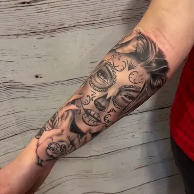 Eine Person hat eine Tätowierung mit dem Gesicht einer Frau auf dem Arm
