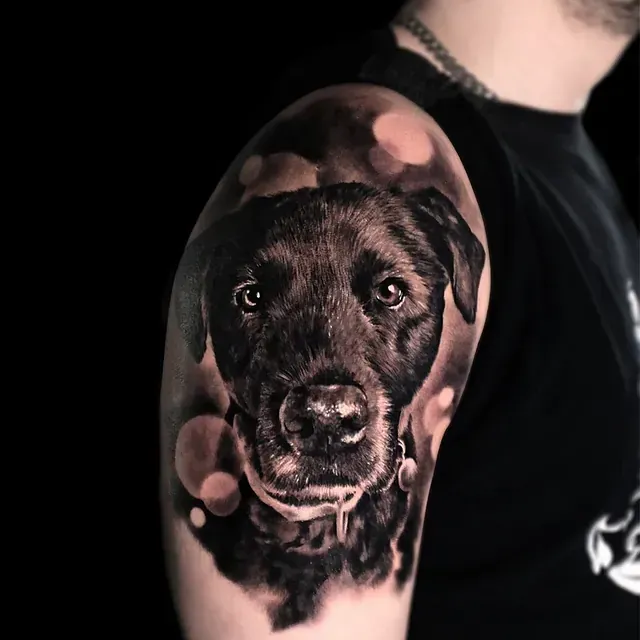 Ein Mann hat die Tätowierung eines schwarzen Hundes auf seinem Arm.