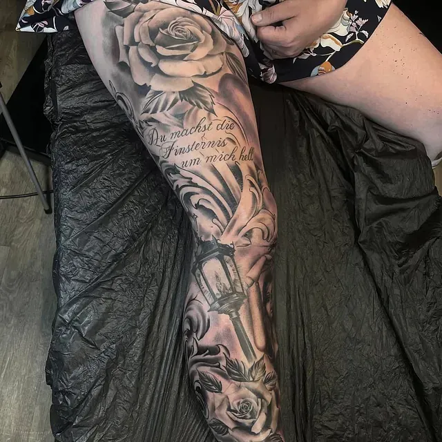 Eine Frau hat ein Tattoo mit Rosen und einer Laterne auf ihrem Bein