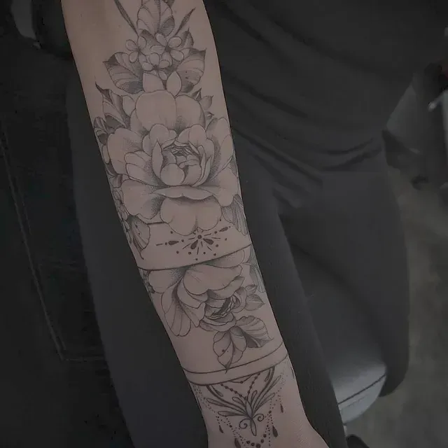 Eine Frau hat eine Blumentätowierung auf ihrem Unterarm.