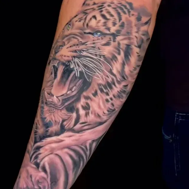 Eine Person hat eine Tigertätowierung auf dem Arm