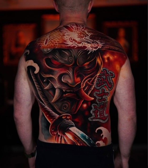 Rückansicht einer Person mit einem großen rot-schwarzen Dämonen-Tattoo auf Rücken und Schultern.