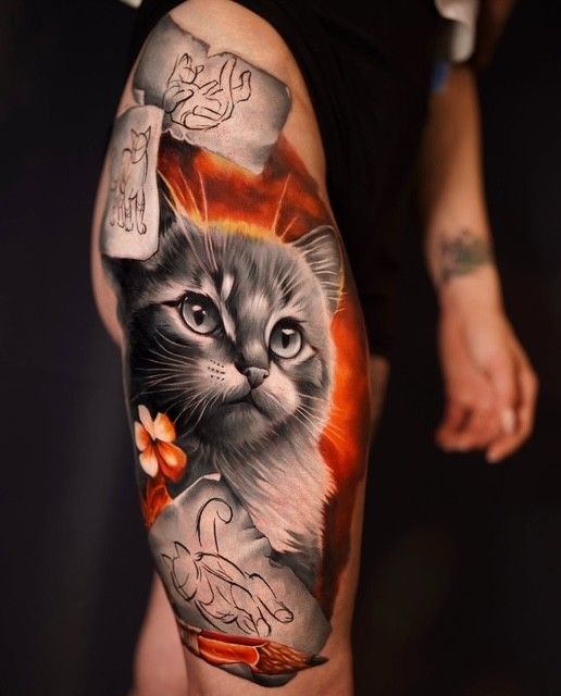 Buntes Katzen-Tattoo auf dem Oberarm einer Person mit orangefarbenen, schwarzen und grauen Schattierungen