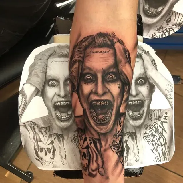 Eine Person hat eine Tätowierung des Jokers auf dem Arm