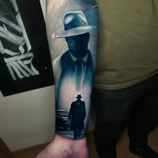 Ein Mann hat eine Tätowierung eines Mannes mit Hut auf seinem Arm.