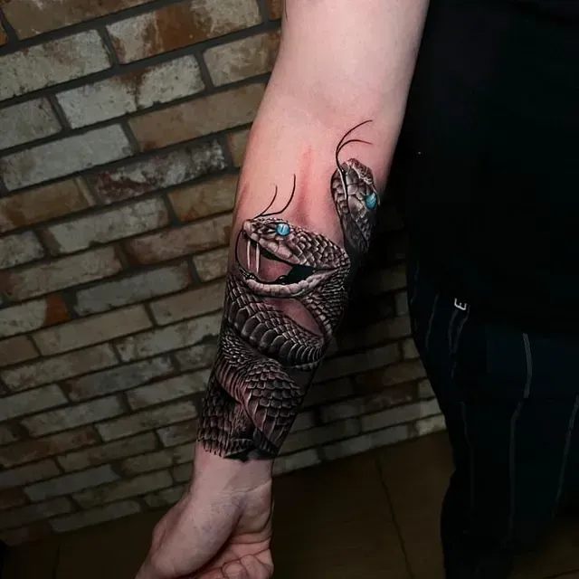Eine Person hat eine Schlangentätowierung auf dem Unterarm.