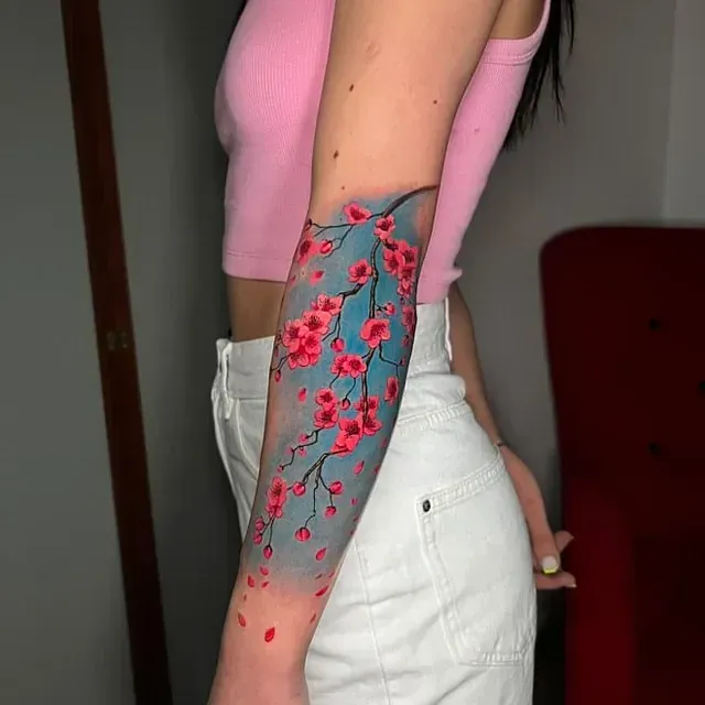 Eine Frau mit einer Kirschblütentätowierung auf dem Arm.