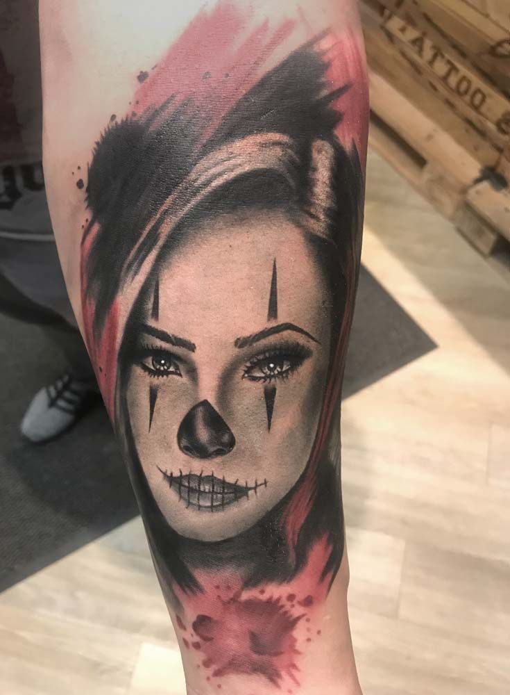 Eine Frau mit einem Clowngesicht-Tattoo auf dem Arm.