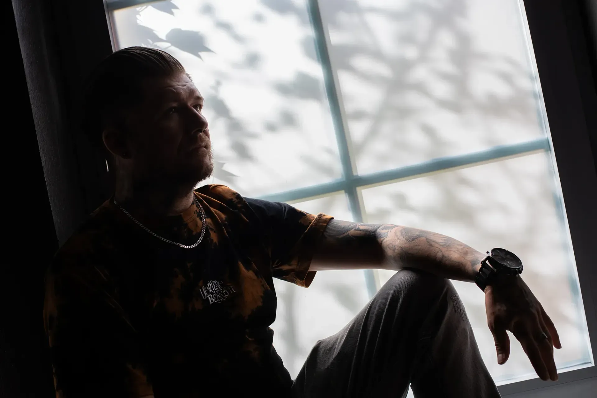 Ein Mann sitzt vor einem Fenster und schaut hinaus.