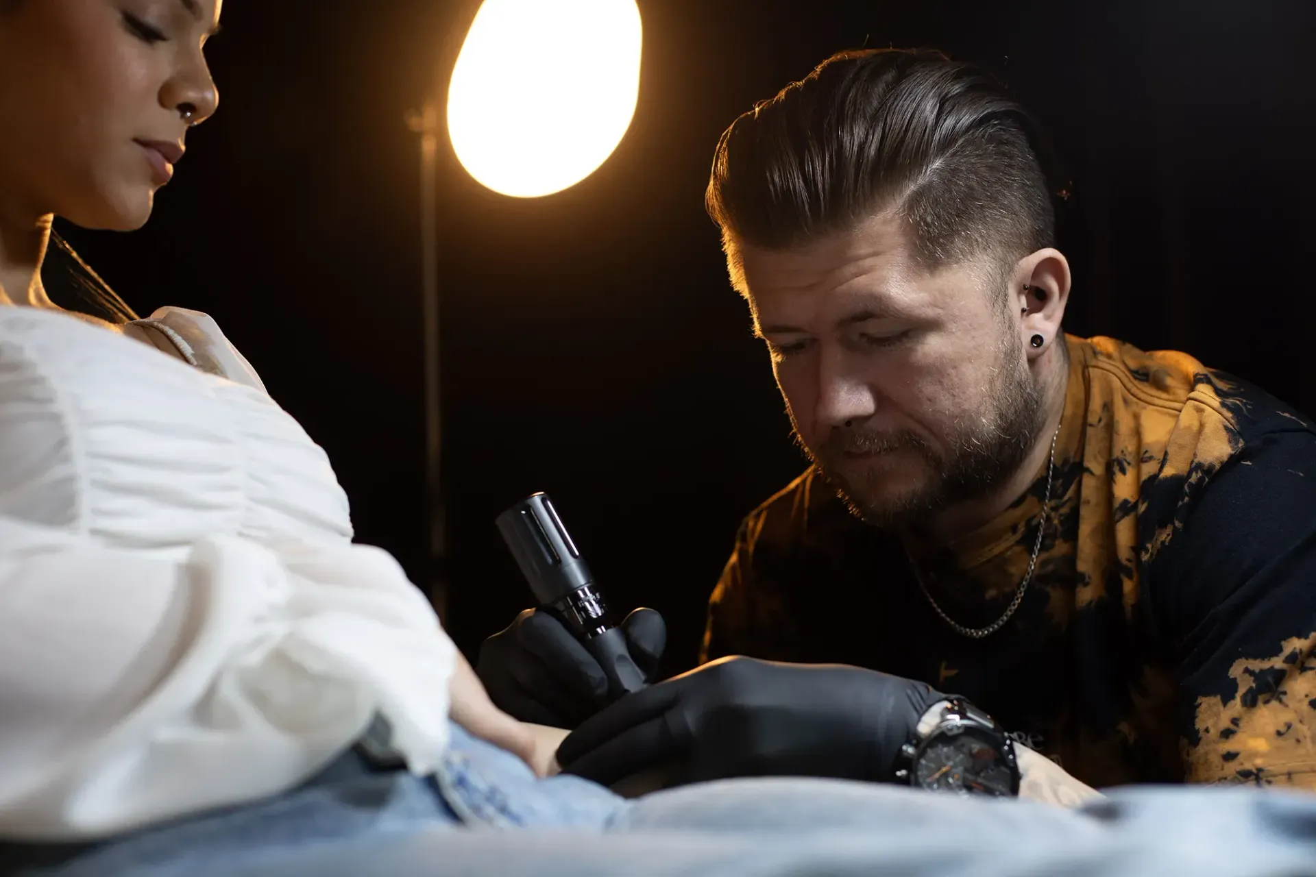 Ein Mann lässt sich auf den Arm einer Frau tätowieren.