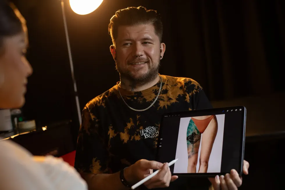 Ein Mann hält ein Tablet mit dem Bild einer Tätowierung darauf.