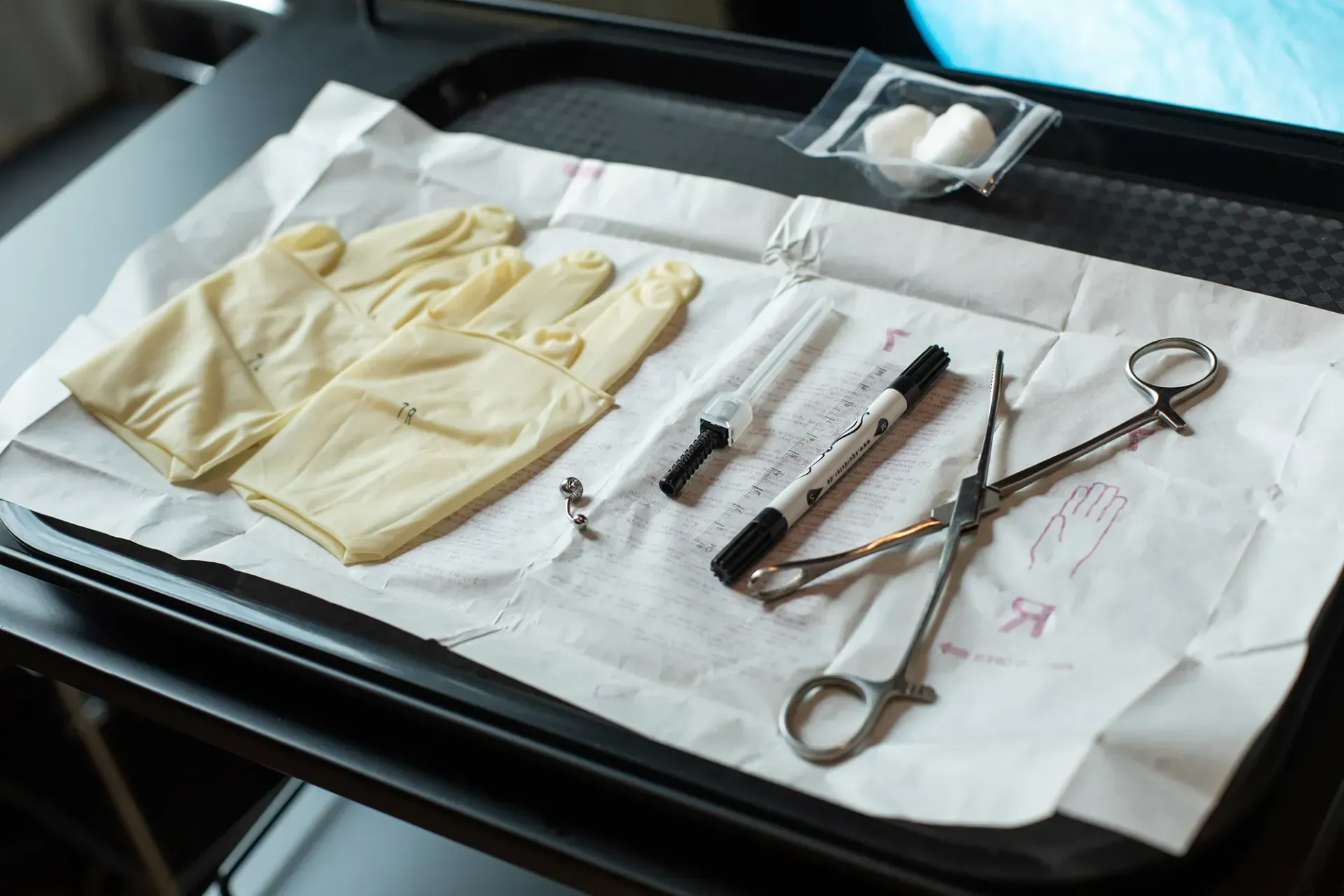 Ein Tablett mit Handschuhen, Spritzen und Scheren darauf