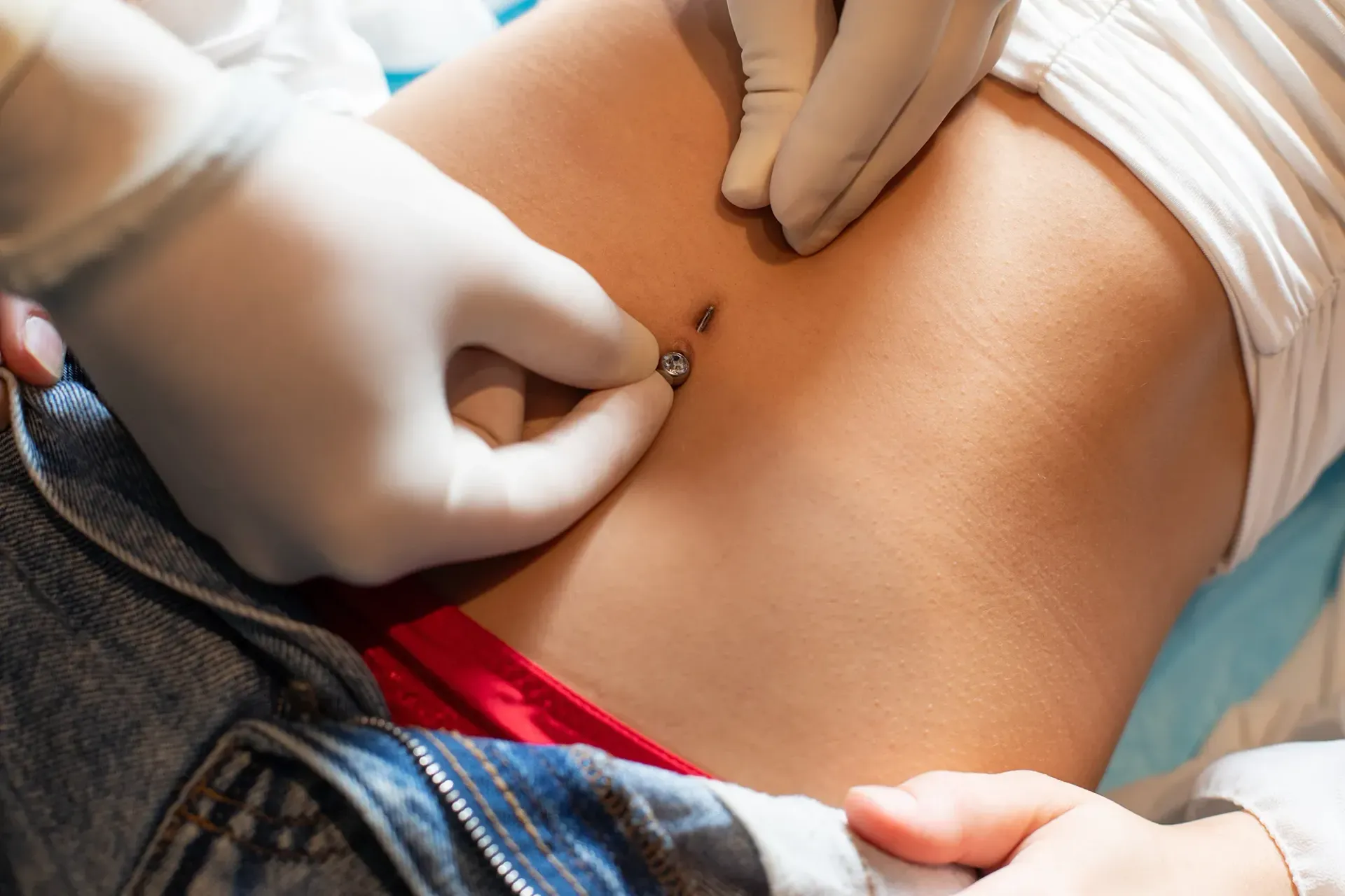 Eine Frau lässt sich von einem Arzt den Bauch piercen.