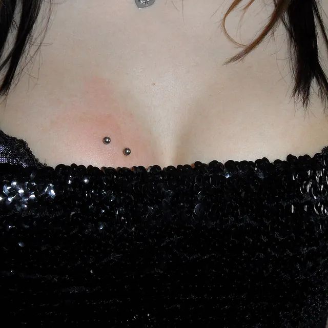 Eine Nahaufnahme der Brust einer Frau mit zwei Piercings