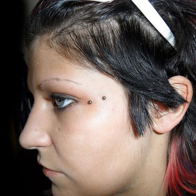 Eine Nahaufnahme des Gesichts einer Frau mit zwei Piercings in ihren Augenbrauen