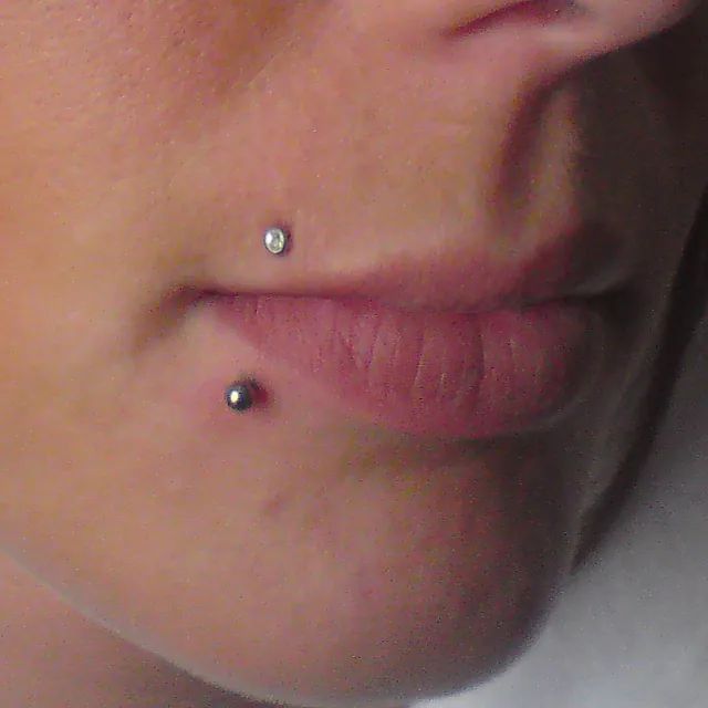 Eine Nahaufnahme des Gesichts einer Frau mit zwei Piercings auf den Lippen.