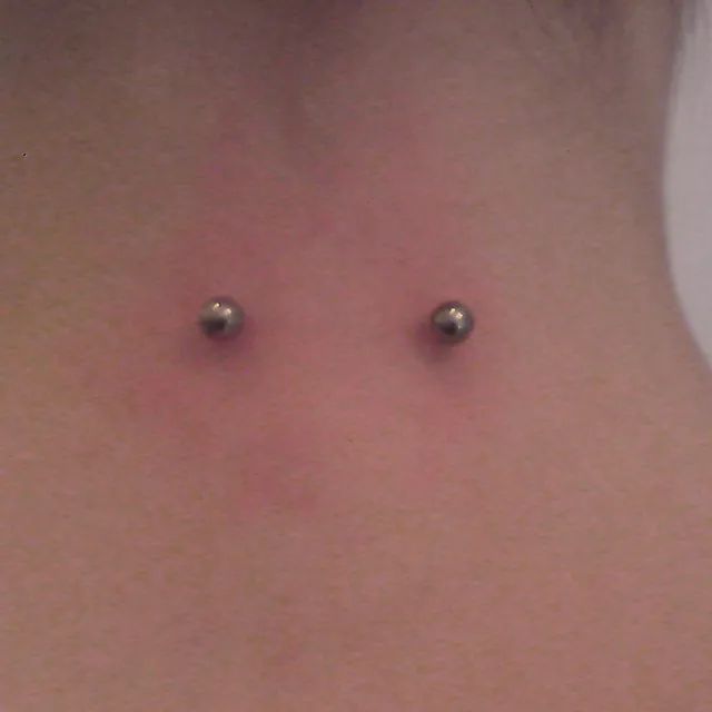 Eine Nahaufnahme vom Hals einer Frau mit zwei Piercings.