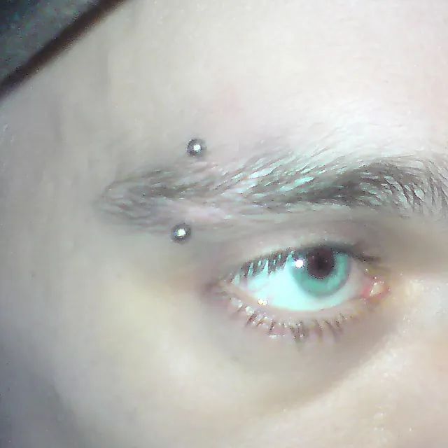 Eine Nahaufnahme des Auges einer Person mit einem Piercing in der Augenbraue.