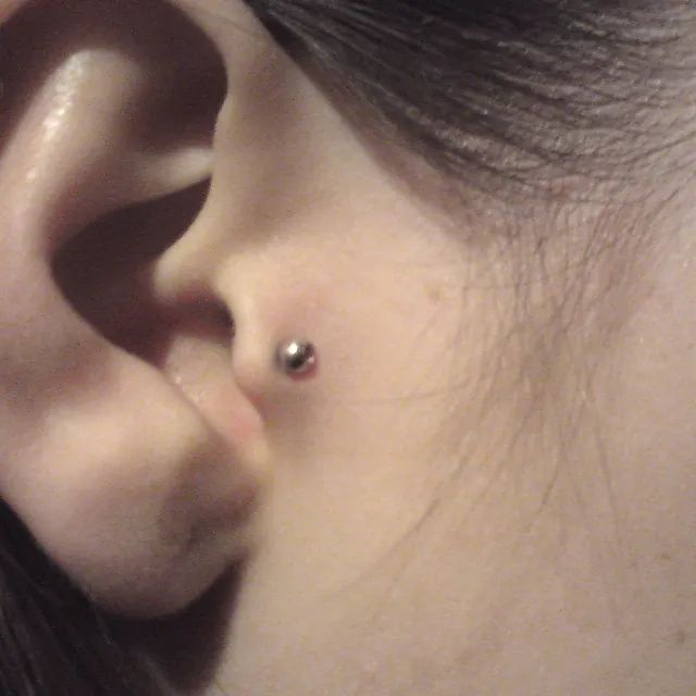 Eine Nahaufnahme des Ohres einer Frau mit einem Piercing