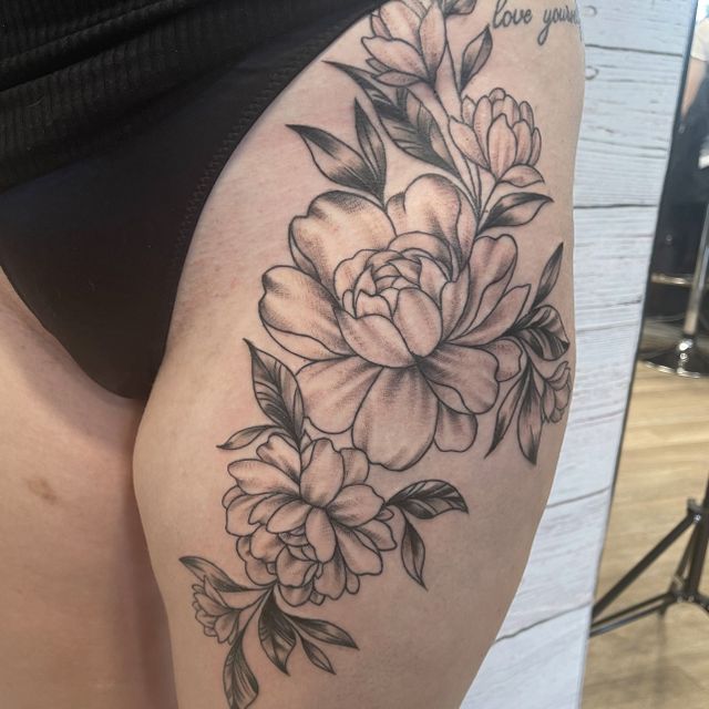 Eine Frau hat eine Blumentätowierung auf ihrem Oberschenkel