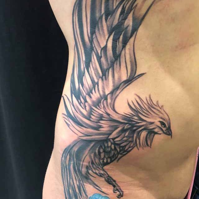 Ein Mann hat eine Phönix-Tätowierung auf seiner Seite.
