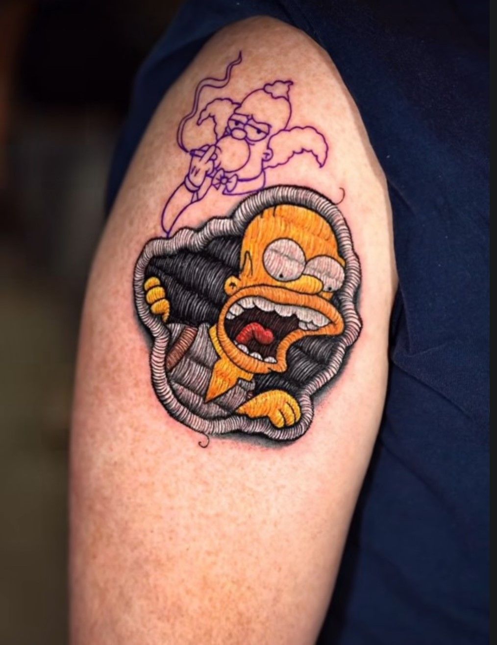 Eine Person hat eine Tätowierung von Homer Simpson auf dem Arm
