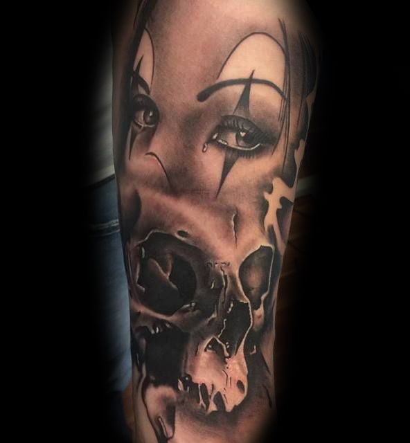 Ein schwarz-weißes Tattoo einer Frau mit Clownsgesicht und Totenkopf.