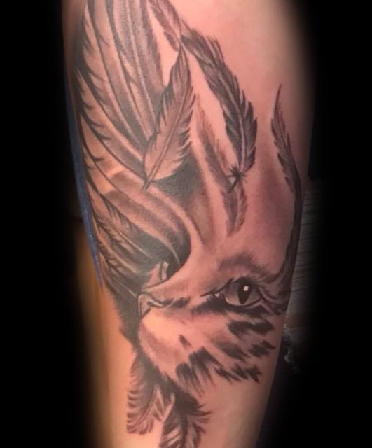 Eine Person hat eine Tätowierung eines Adlers mit Federn auf ihrem Bein.